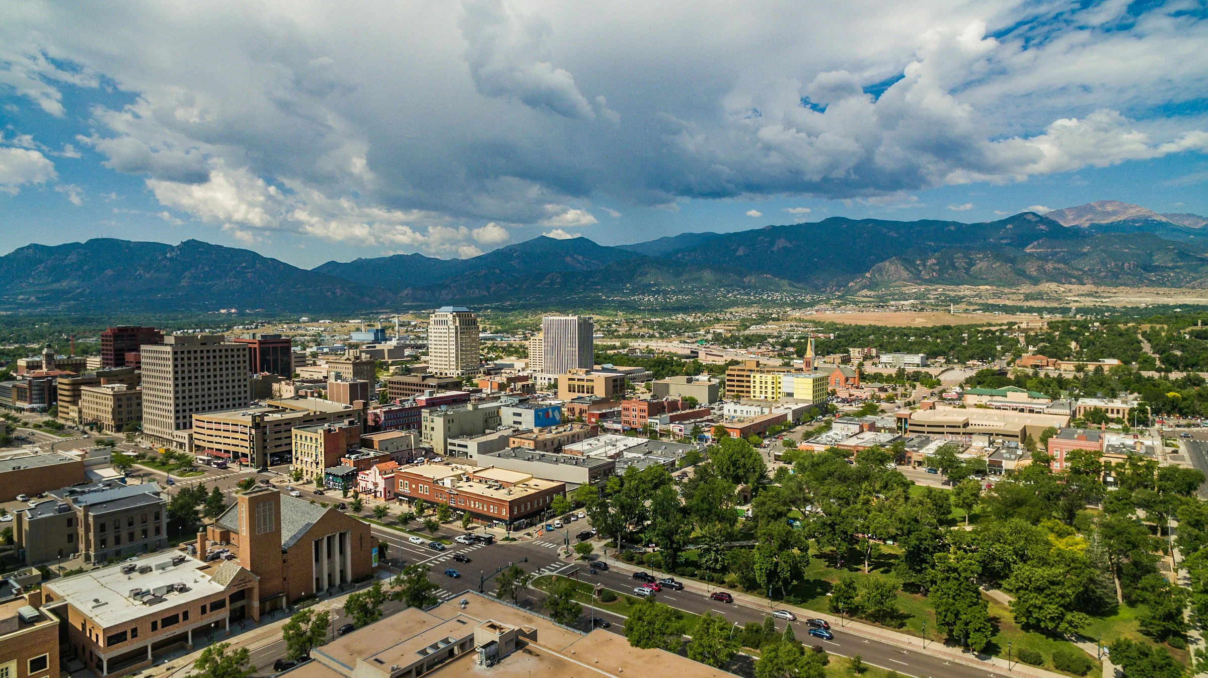 Aerial view of downtown Colorado Springs and Acacia Park, with Pikes Peak behind