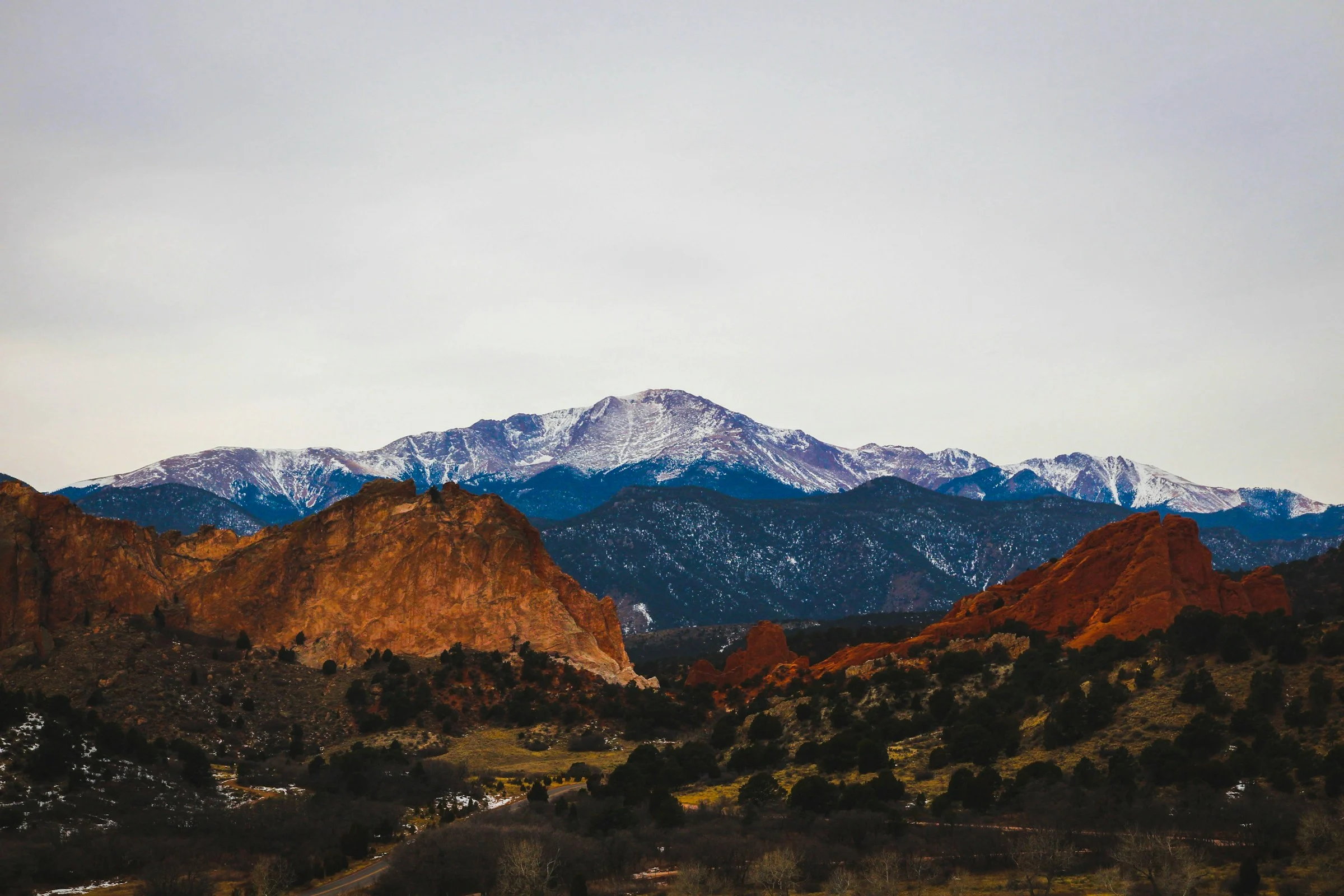 Pikes Peak in snow above red rock formations on a clear day